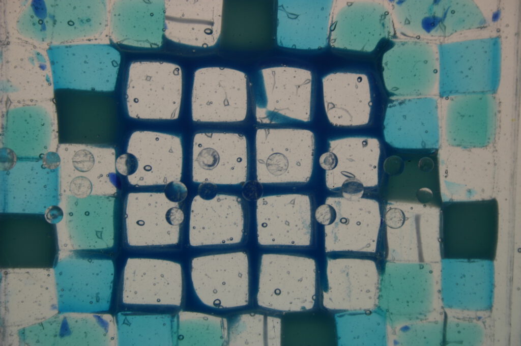 A close-up of a blue and white mosaic glass piece showing rounded squares and visible internal bubbles.