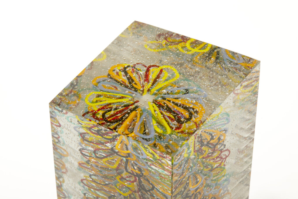 A close-up top-down view of the sculpture, revealing the intricate, layered spirographical flower patterns within the glass.