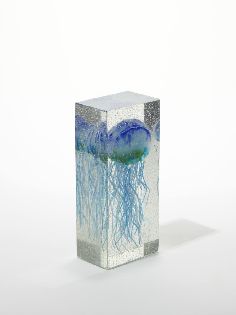 A side view of the clear glass block, highlighting the depth and detail of the fused jellyfish.
