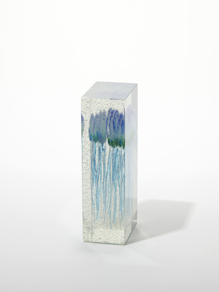 A side view of the clear glass block, highlighting the depth and detail of the fused jellyfish.