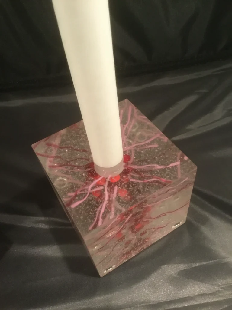 A top-down view of a clear glass candle holder with a candle inserted, showing the chaotic red internal design.