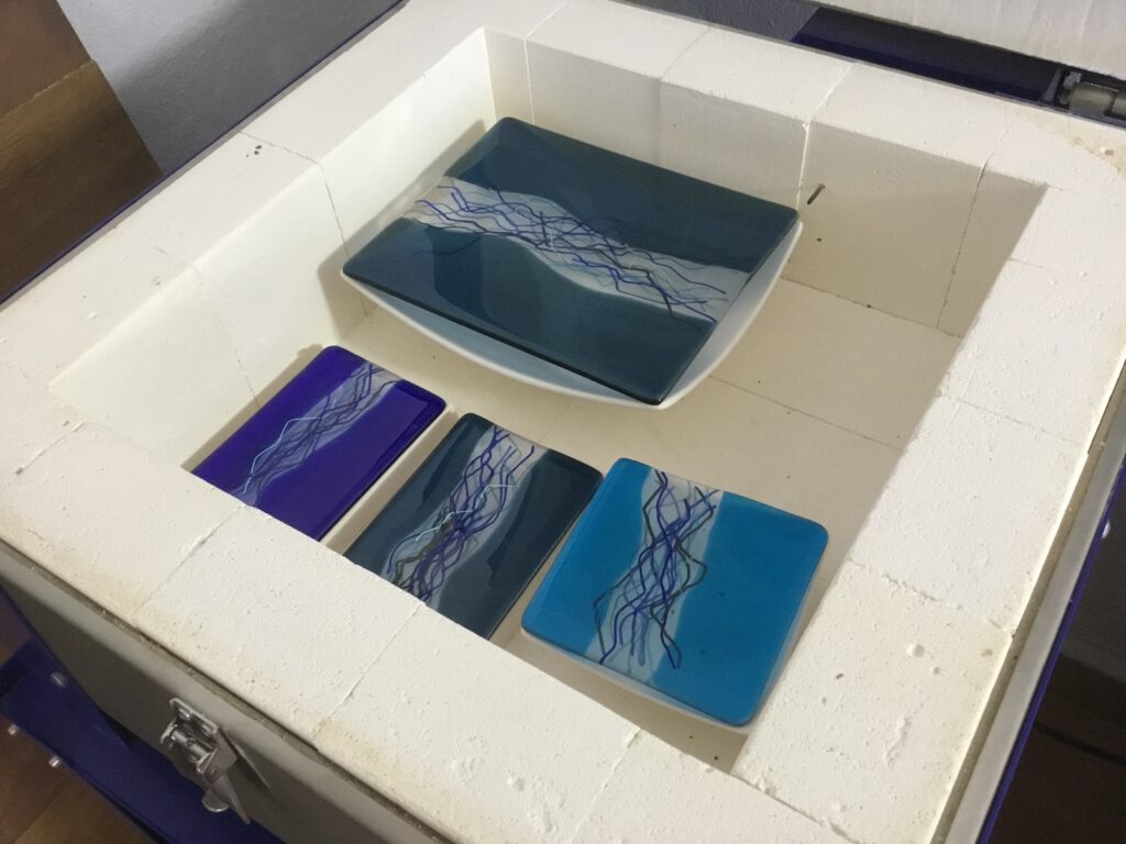River dishes in different shades of blue placed in a kiln mold, showing the glass slumping process.