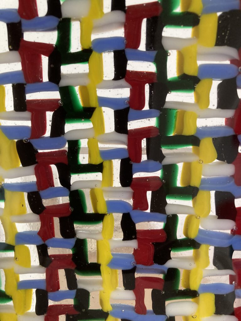 A close-up of a colourful mosaic pattern made from a jumble of various solid-coloured glass shards.