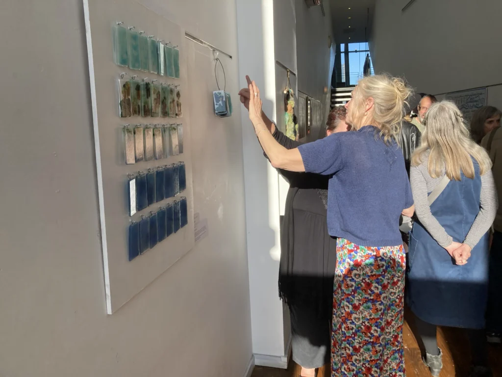 People in a room looking at the artwork piece of Rising Tides.
