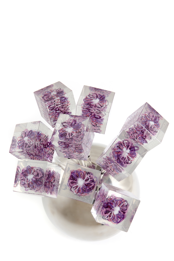A cluster of transparent glass stems topped with fused purple daisy flowers, arranged like a bouquet.