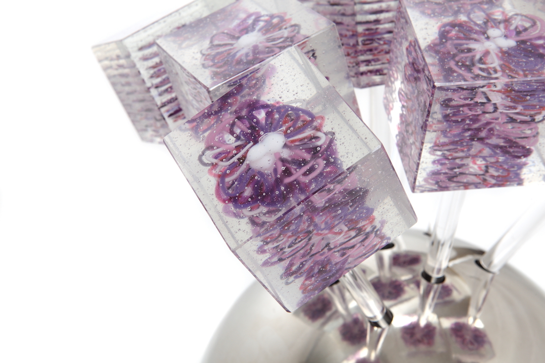 A close-up of the purple glass daisies, showing the delicate loops and layered glass details.