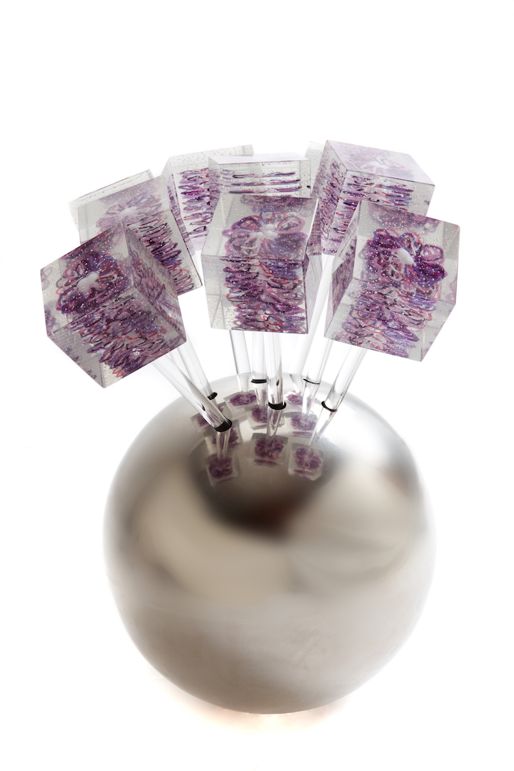 A beautiful bouquet of purple glass daisies with intricate petals displayed in a sleek silver vase.